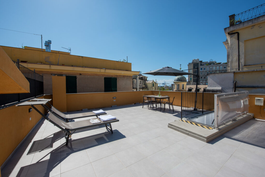 Area solarium con lettini prendisole sulla grande terrazza dell'appartamento vicino al Palazzo della Regione a Genova, nel centro storico.